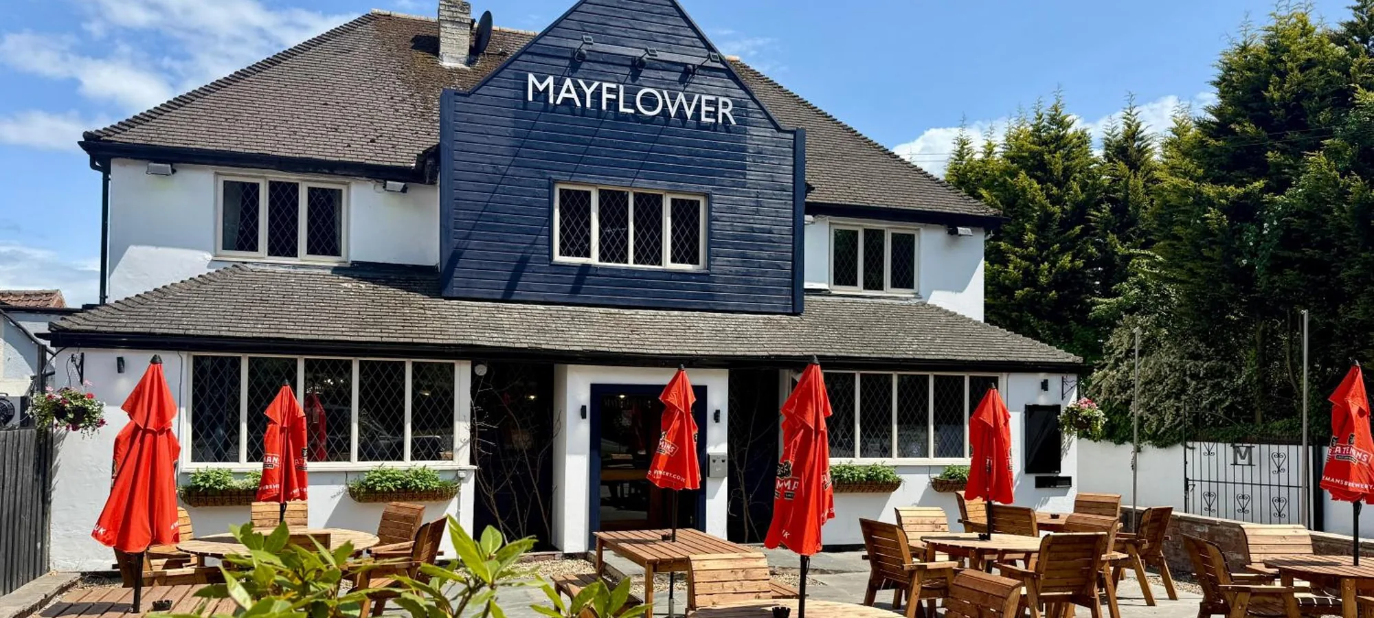 The front of The Mayflower with its terrace tables and parasols, seen from High Street