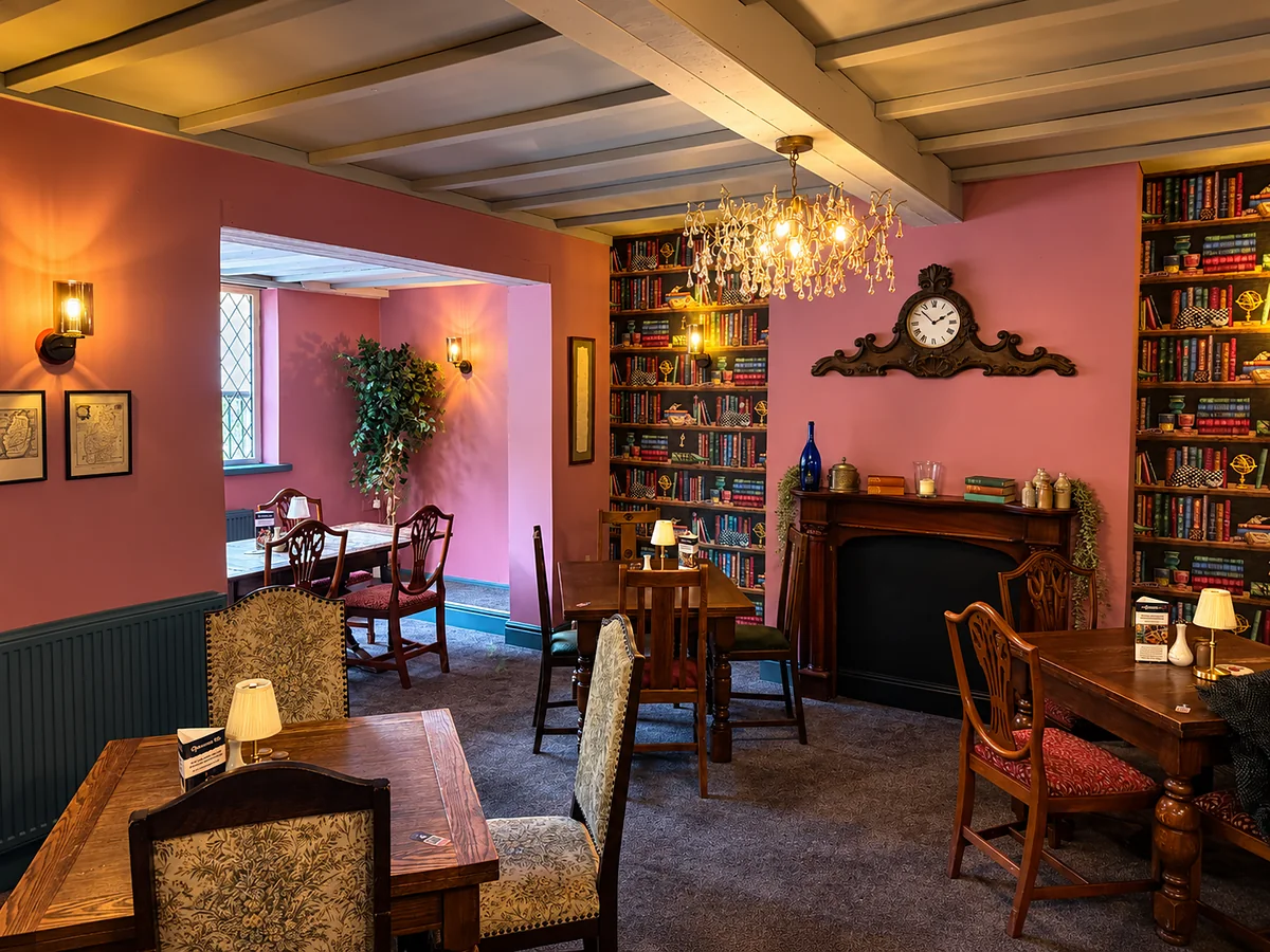 The dining room at The Mayflower — a beamed ceiling, a chandelier, a fireplace and bookshelf walls